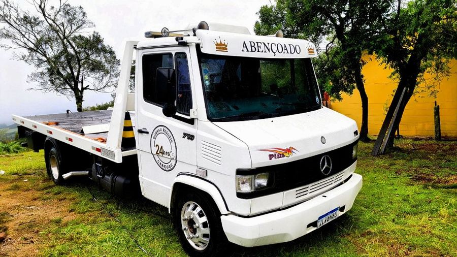 Caminhão guincho plataforma branco do Abençoado, com o nome na cabine, estacionado na grama