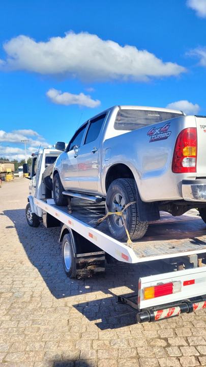 Picape 4x4 prata amarrada com cintas na plataforma do guincho