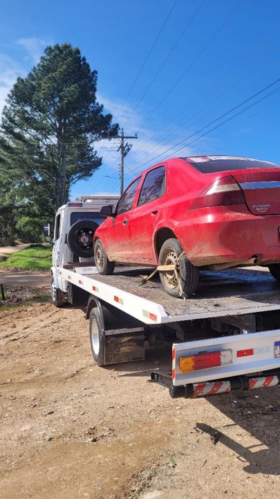 Sedan vermelho coberto de barro sobre o guincho